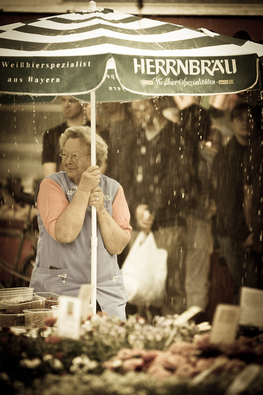 Marktfrau im Regen unter dem Schirm